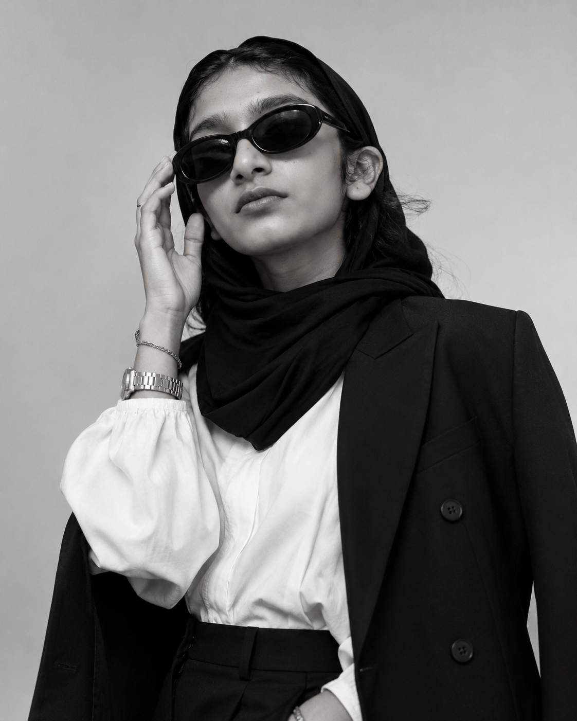 Haseefa wearing a black blazer, white shirt, and black hijab in a stylish professional portrait.